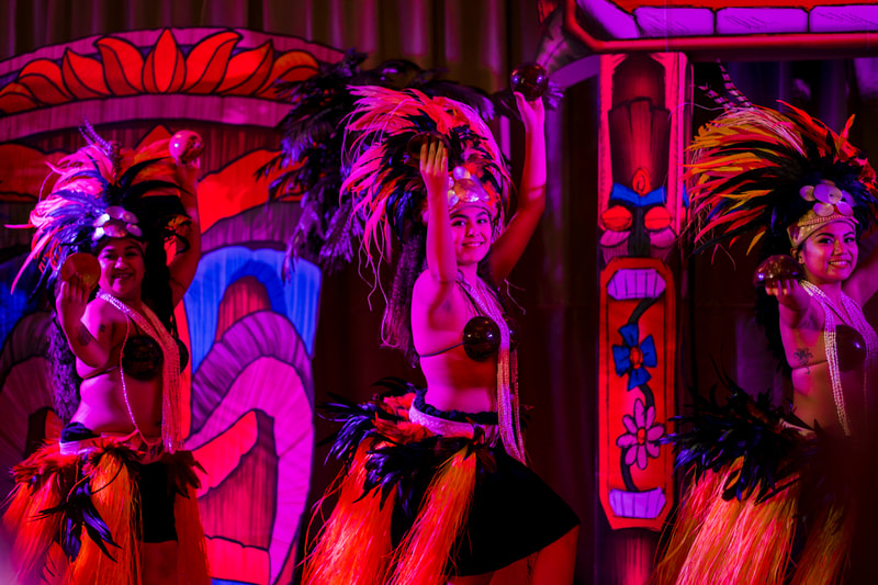 Neon lit Polynesian dancers feathered headdresses show
