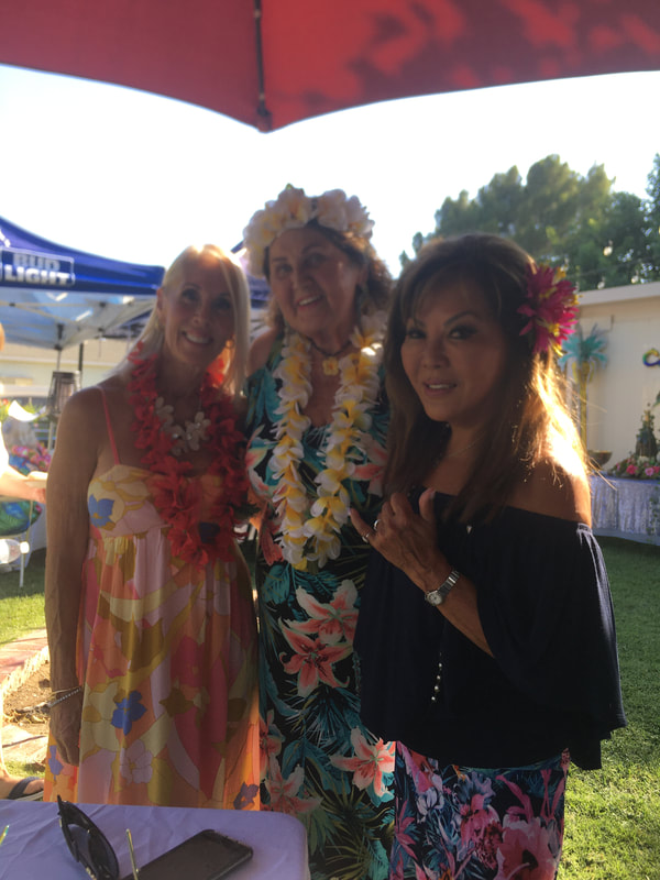 Women wearing lei at outdoor luau event tent
